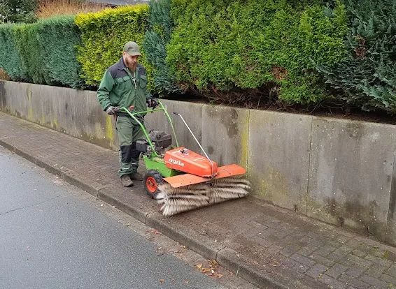 Reinigung eines Gartenwegs mit Besen und Hochdruckreiniger